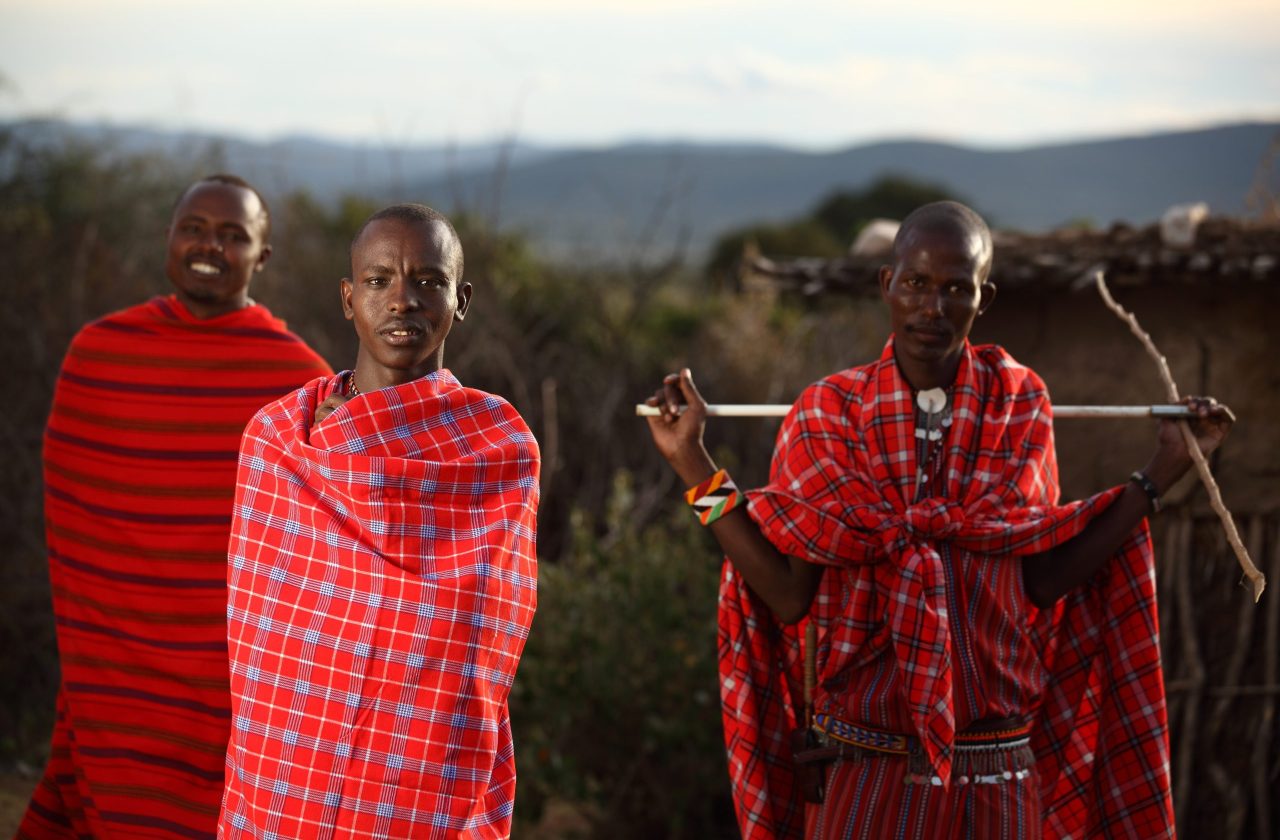 MASAI MARA, KENYA - Jan 01, 2013: A shallow focus shot of three African males with blankets wrapped around them